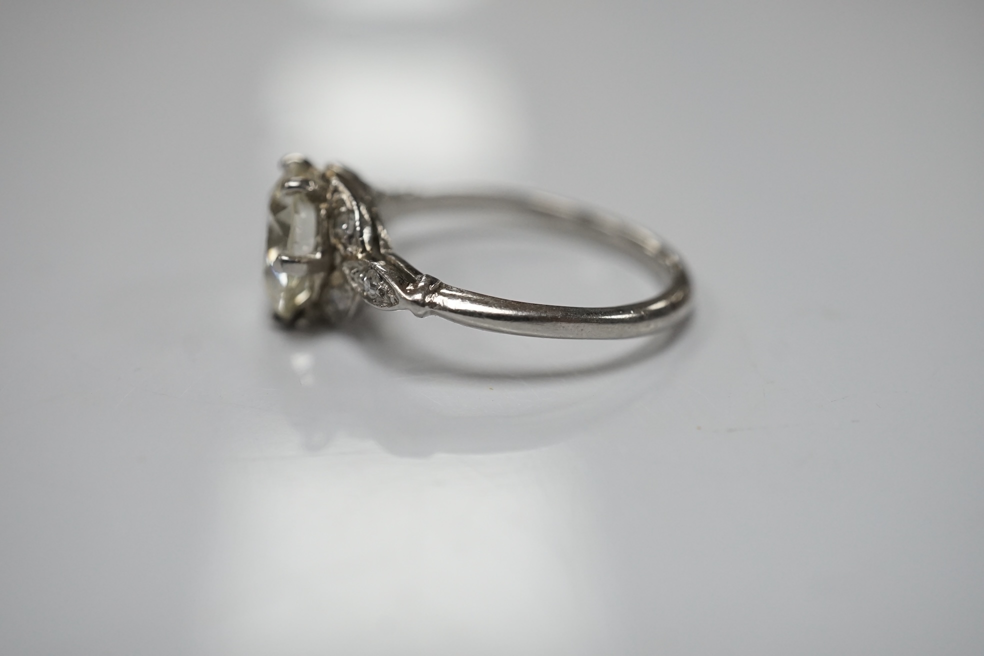 A platinum and single stone diamond set ring, with six stone diamond chip set foliate shoulders, the centre stone weighing 1.60ct, size H/I, gross weight 3.1 grams. Condition - fair